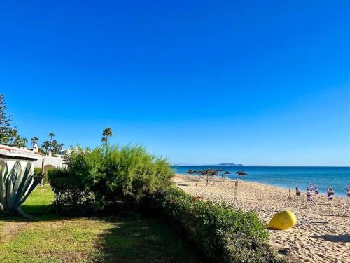 a beach with people on the sand and the ocean at Beach Front Villa Al Andalus in Restinga Smir