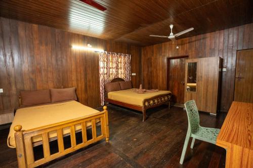 a bedroom with two beds and a table and a chair at Hill Valley Farm House in Nelliyampathy