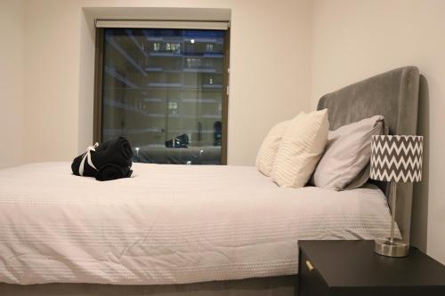 a bed with a backpack sitting on top of it at Luxury 2 Bed 2 Bath City Apartment in London