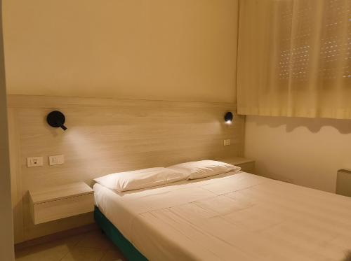 a bedroom with a white bed with a window at Hotel I Platani in Siena