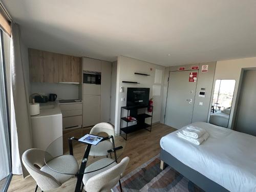 a bedroom with a bed and chairs and a kitchen at New Douro 908 with parking in Vila Nova de Gaia