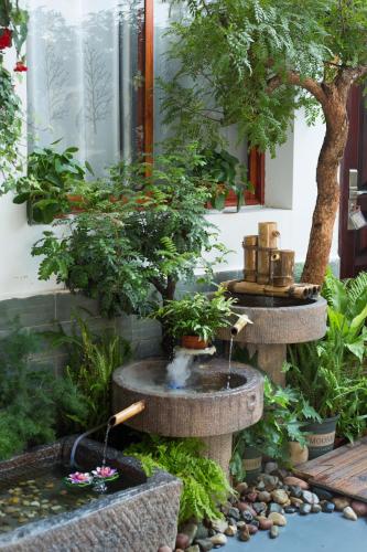 a garden with a water fountain and bonsai trees at 建水县井宿客栈 in Jianshui