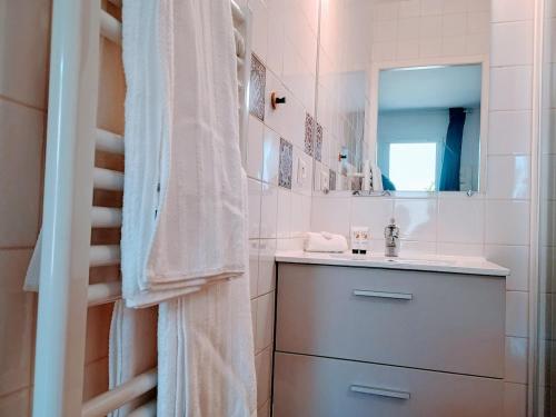 ein weißes Badezimmer mit Waschbecken und Spiegel in der Unterkunft Studio Beau Soleil in LʼIsle-sur-la-Sorgue