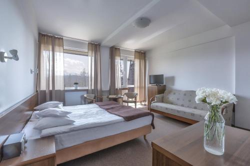 a bedroom with a bed and a vase of flowers on a table at Rysy in Bukowina Tatrzańska