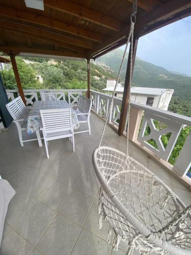 a porch with chairs and a table and a swing at Villa Nefeli in Piqeras
