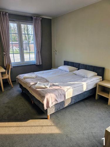 a large bed in a bedroom with a large window at Noce i Dnie in Pierkunowo