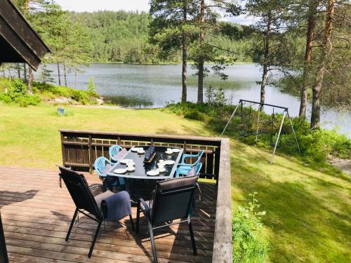 a table and chairs on a deck with a view of a lake at Fredelig og landlig hytte in Iveland