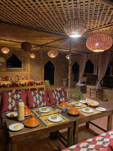 a table with bowls and plates on it in a room at Riad La Perle Tamnougalte in Agdz