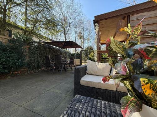 a patio with a couch and a table and chairs at VELUWE CHALET HOENDERLOO Private Jacuzzi, Park Swimming Pool and Children's Entertainment in Hoenderloo