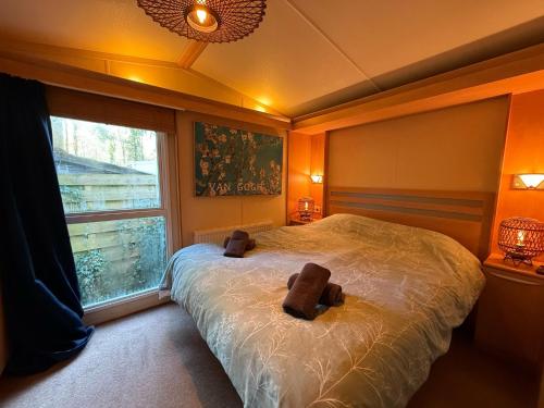 a bedroom with a large bed and a window at VELUWE CHALET HOENDERLOO Private Jacuzzi, Park Swimming Pool and Children's Entertainment in Hoenderloo