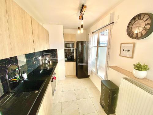 une cuisine avec un évier et une horloge murale dans l'établissement Le Prestige Terrasse-Cocon familial cosy, Billard & Jacuzzi avec vue sur Paris, au Blanc-Mesnil