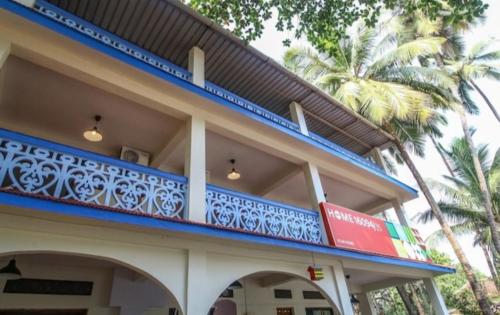 a building with a blue balcony with palm trees at Star Home in Anjuna