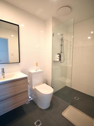 a bathroom with a toilet and a glass shower at Sydney Private Home I in Bankstown