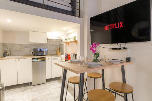 Il comprend une cuisine avec une table et des chaises ainsi qu'une télévision murale. dans l'établissement Caractère et Raffiné en hypercentre, à Lyon