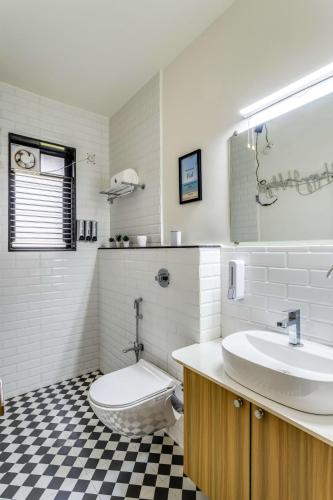 a bathroom with a sink and a toilet in it at Mini Paradise Apartment by tisyastays in Candolim