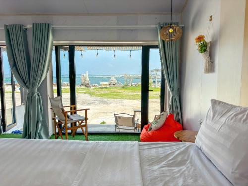 a bedroom with a bed and a view of the beach at Long Vĩ hotel - đảo Phú Quý in Cu Lao Thu