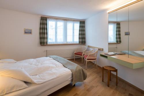 a bedroom with a bed and a desk and chairs at Hotel Post in Bivio