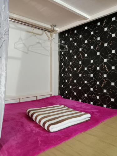 a room with a towel on a purple rug at STPhostel in Patong Beach