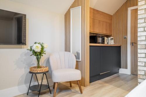 a room with a white chair and a table with a vase of flowers at Paradise Apartments in York