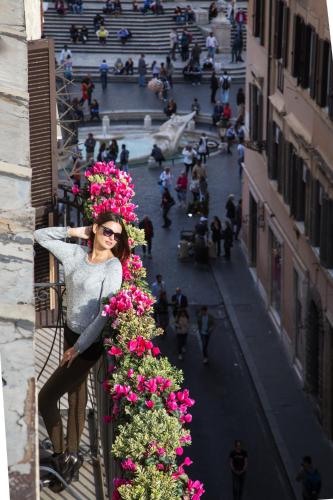 a woman standing on a balcony with flowers at The Inn at the Spanish Steps Luxury Collection - The Inn at the Spanish Steps in Rome