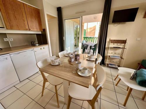 - une cuisine avec une table en bois et des chaises blanches dans l'établissement nid douillet au milieu des pins entre lac et océan, à Carcans