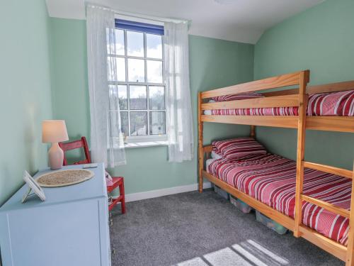 ein Schlafzimmer mit zwei Etagenbetten und einem Schreibtisch in der Unterkunft Morton Mains Steading Cottage in Thornhill