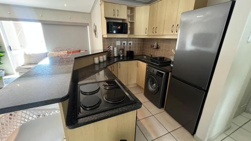 a kitchen with a stainless steel refrigerator and a dishwasher at La Caribe Unit 01 in Jeffreys Bay