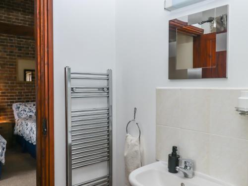 ein Badezimmer mit Waschbecken und Spiegel in der Unterkunft Daisy Cottage in Bridport