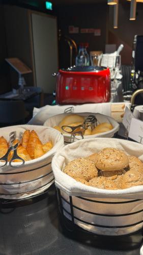 three trays of bread and pastries on a table at Golden Lisbon Hotel in Lisbon