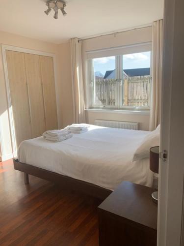 ein Schlafzimmer mit großem Bett und Fenster in der Unterkunft Tieveragh in Aviemore