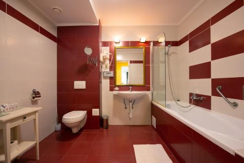 a bathroom with a toilet and a sink and a shower at Calimbra Wellness Hotel Superior in Miskolctapolca