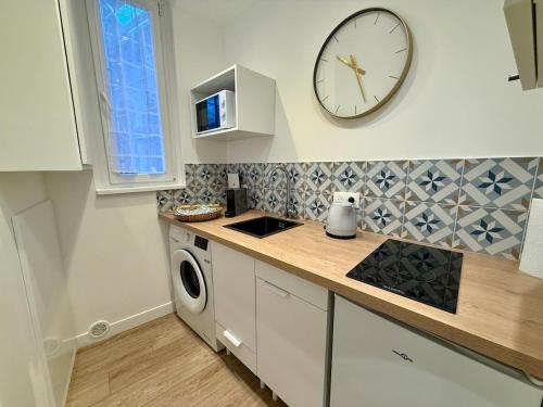 une cuisine avec une horloge murale et un lave-linge dans l'établissement P20 clim jacuzzi proche centre, à Nancy