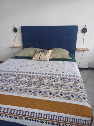 a bed with a blue headboard and pillows on it at Honey room city center in Papeete