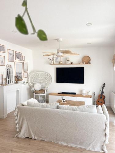 Il comprend un salon doté d'un canapé blanc et d'une télévision à écran plat. dans l'établissement Villa Cinta, piscine chauffée, 5 min de la plage, à Tarnos