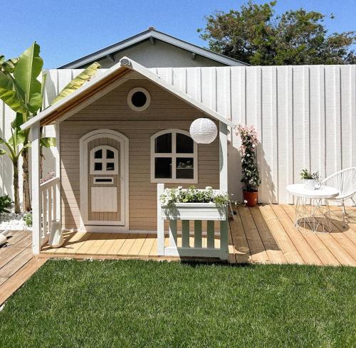 une maison pour chiens bruns avec une table sur une terrasse dans l'établissement Villa Cinta, piscine chauffée, 5 min de la plage, à Tarnos