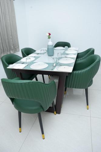 a dining table with green chairs around it at The White Chateau by Chakolas Hospitality in Trichūr