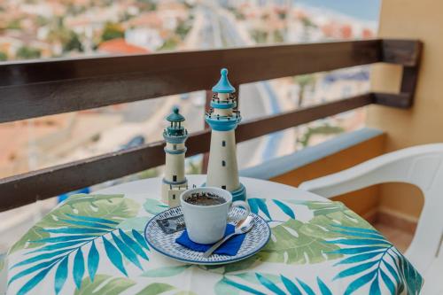 a table with a cup of coffee and two lighthouse figurines on it at Hotel Apartamentos Londres La Manga in La Manga del Mar Menor
