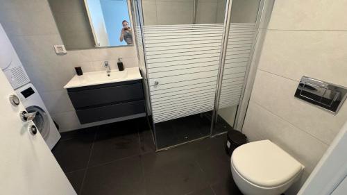 a man taking a picture of a bathroom with a toilet and sink at סי סייד אילת סוויטה משפחתית 2 חדרים עם מרפסת ונוף לים in Eilat