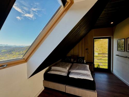 a bedroom with a bed with a large window at Bacówki Resort in Ochotnica Górna
