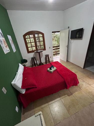 a bedroom with a red bed with a red blanket at Pousada Flor da Mata in Nova Lima