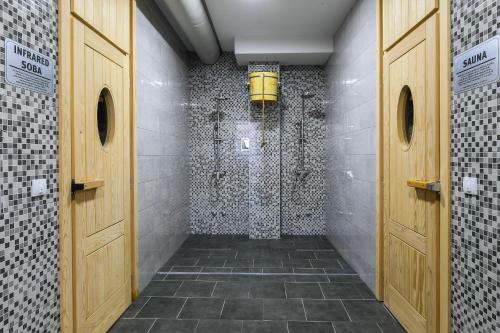 a bathroom with a walk in shower with wooden doors at Alexander Resort in Sopot
