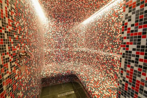 a tiled bathroom with a red and black tile wall at Alexander Resort in Sopot
