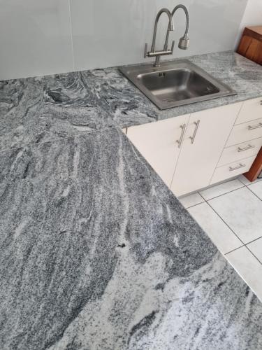 a kitchen with a sink and a granite counter top at Newly Furnished Condominium in the Heart of Quezon City near Top Philippine Hospitals in Manila