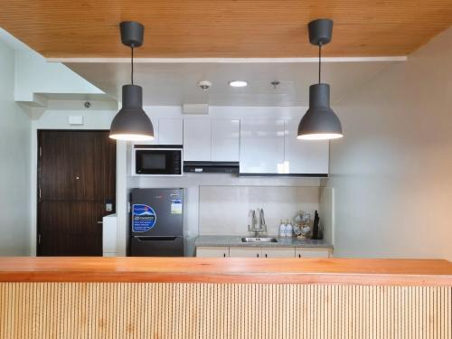 a kitchen with white cabinets and a black refrigerator at Newly Furnished Condominium in the Heart of Quezon City near Top Philippine Hospitals in Manila