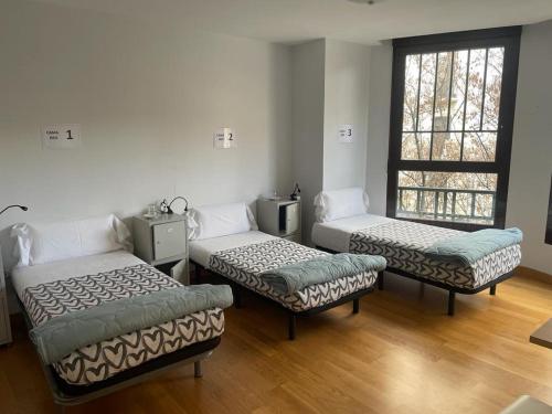 a room with three beds and a window at Aloha Hostel in Pamplona