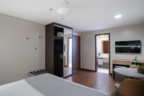 a room with a bed and a living room at Jk Premium Hotel e Eventos in Londrina