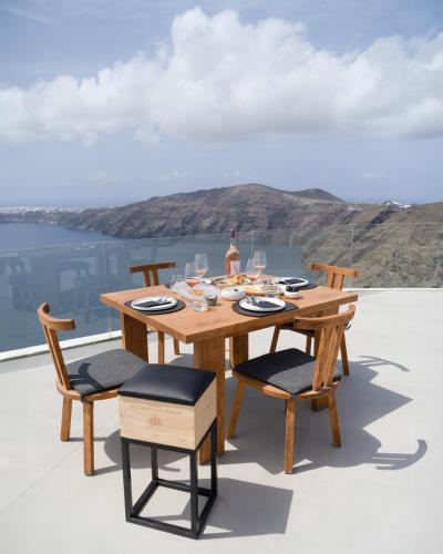 a wooden table and chairs on a deck at Rocabella Santorini Hotel & Spa in Imerovigli