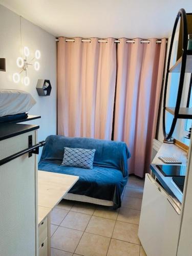 - un salon avec un canapé bleu et des rideaux dans l'établissement Studio Marais square du temple Parking, à Paris