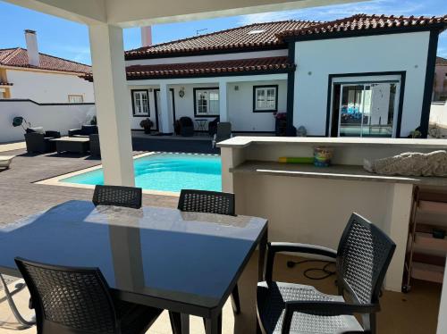 a patio with a table and chairs and a swimming pool at Spacious quiet charming villa with private pool and close to Lisbon in Monte de Lucas