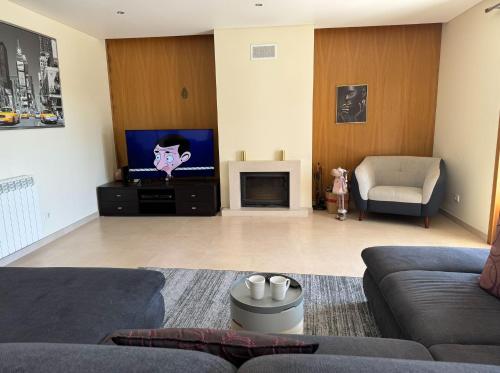 a living room with a couch and a flat screen tv at Spacious quiet charming villa with private pool and close to Lisbon in Monte de Lucas